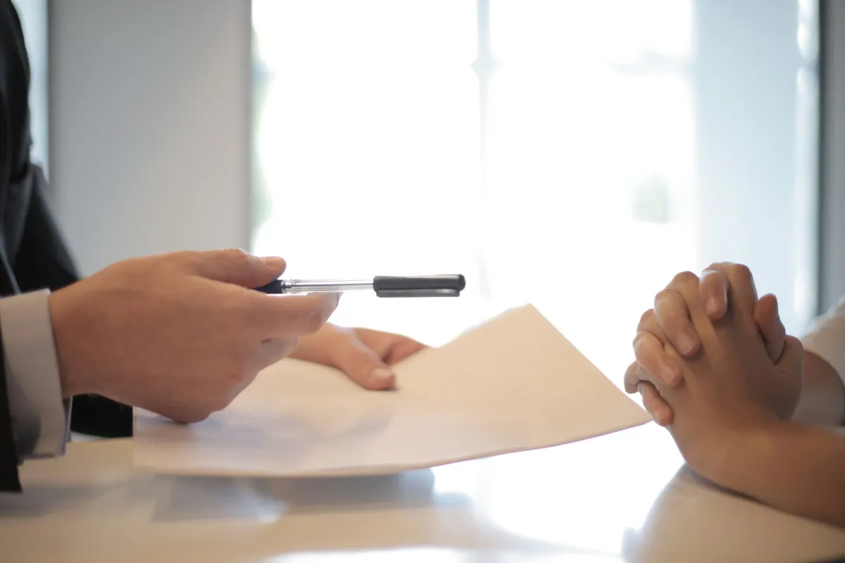 Manager handing a job offer contract to a candidate to sign