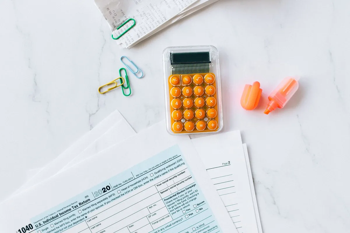IRS tax forms, a calculator, and paper clips on a white desk